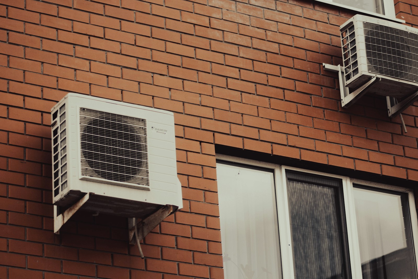 Air conditioners are attached to a brick building.